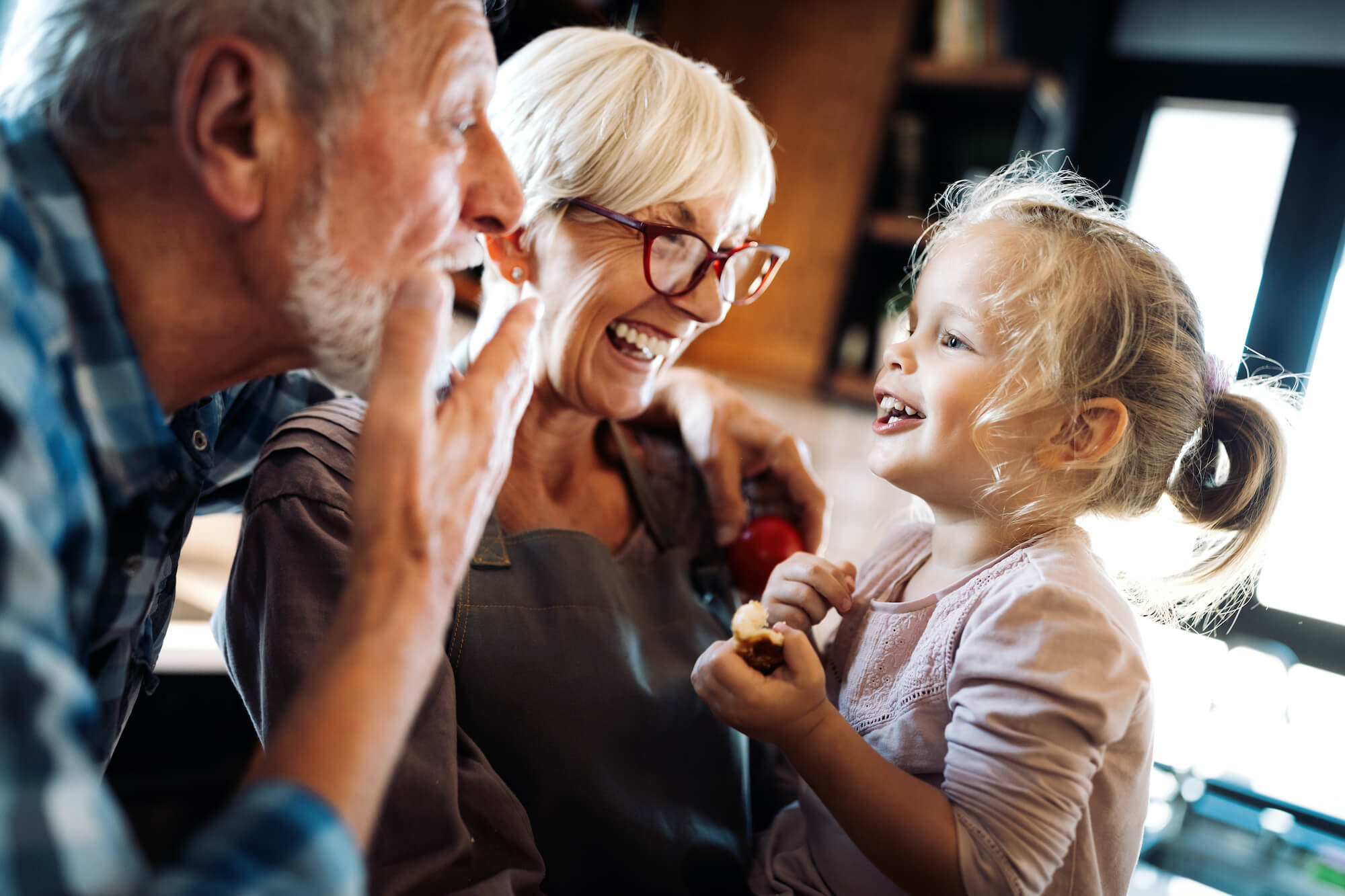 Happy smiling senior grandparents playing with their granddaughter